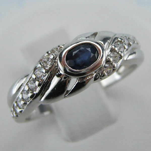 Sterling Silver ring stamped 925 with pattern decorated with oval blue sapphire and round clear Cubic Zirconia stones. It is also white gold or rhodium plated.