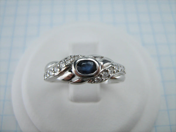 Sterling Silver ring stamped 925 with pattern decorated with oval blue sapphire and round clear Cubic Zirconia stones. It is also white gold or rhodium plated.